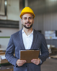 Confident Engineer in Suit with Hard Hat Holding Clipboard at Worksite