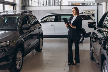 Saleswoman using tablet and working at car dealership