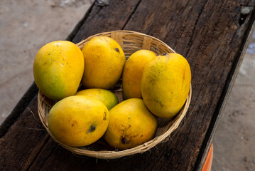 Ripe mango tropical fruit in basket on wooden table at mangoes farm
