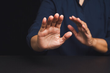 Close-up of man raising hands in defensive gesture on black background, concept of refusal or stop.