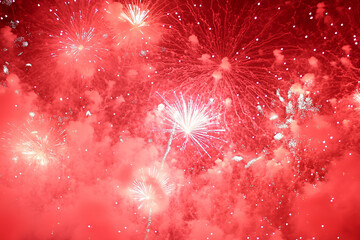 A breathtaking burst of red fireworks illuminates the night sky, filling the frame with radiant light and a sense of festive excitement.