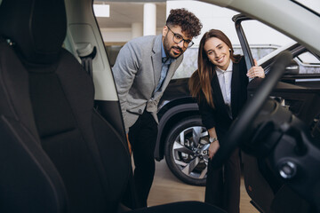 Car dealer showing new vehicle to customer in car dealership