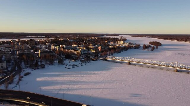 Aerial flying backwards from buildings on banks of frozen Torne River in Tornio, Finland