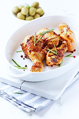 Spicy Chicken Drumsticks with fresh herbs. White wooden background