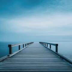 Fototapeta premium Tranquil wooden pier extending into a serene body of water under a pale sky