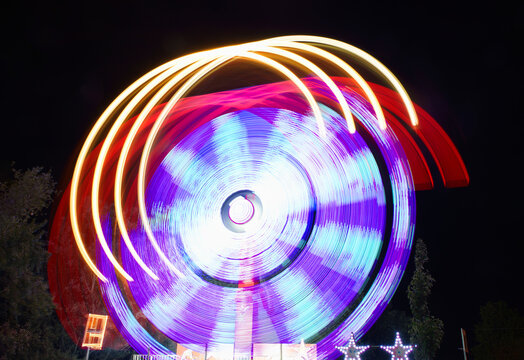 Vibrant long exposure shot of spinning ride at night