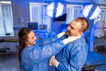 Obraz premium Surgical team shares a laugh. Medical professionals in scrubs share a playful interaction inside a bright hospital room during a break.