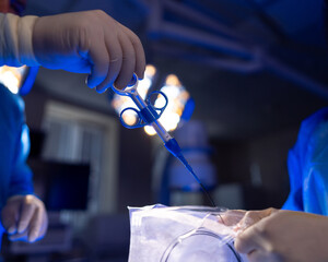 Surgical team executes complex surgery. Surgeons in scrubs perform a delicate procedure with...
