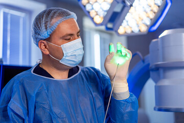 Doctor using laser technology in surgery. A surgeon in a blue gown utilizes laser technology during...