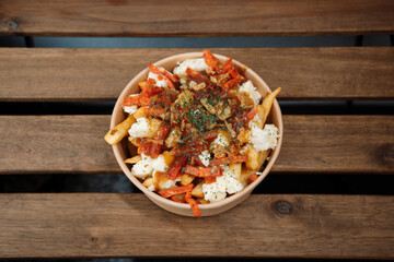 Poutine fries with chees and chorizo in paper takeout container. Delicious freshly prepared meal, perfect for menus, restaurants, or food delivery concepts.