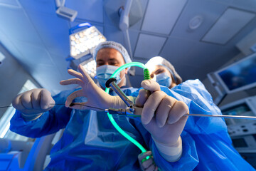 Surgical team conducts advanced ops. Surgical team in scrubs and masks uses advanced tools in a state-of-the-art operating room.