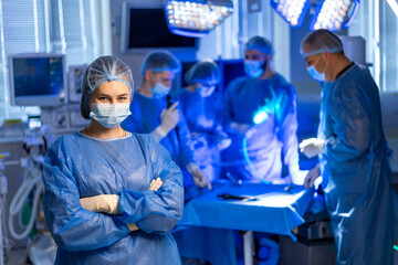 Surgery by hospital staff. Surgeons and nurses in scrubs and masks actively engaged in a surgical...