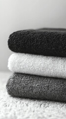 Elegant stack of soft towels in black, gray, and white colors, perfect for a minimalist bathroom decor.