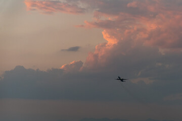 Scenic view of a vibrant sunset over mountains, airplane flying across the colorful sky.