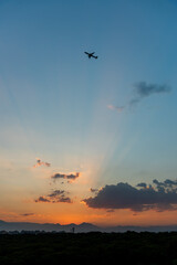 Scenic view of a vibrant sunset over mountains, airplane flying across the colorful sky.