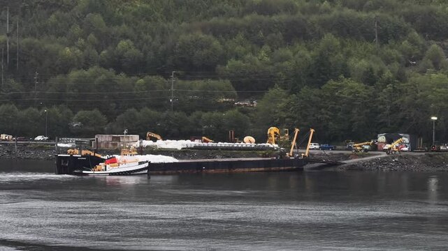 Timelapse of telehandlers moving large bulk rubble and gravel bags from moored cargo ship in USA, Alaska, Ketchikan, Ward Cove