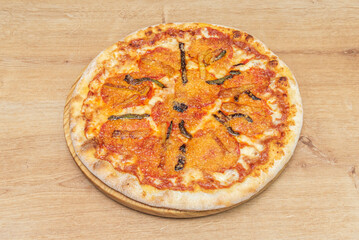 A delicious pizza with strips of peppers and grated cheese on a round wooden board