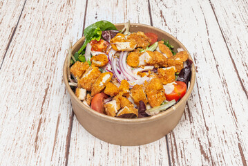 A wonderful salad with crispy chicken inside a cardboard delivery bowl