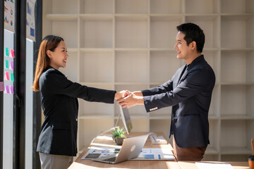 A man shakes hands with a woman in a business setting
