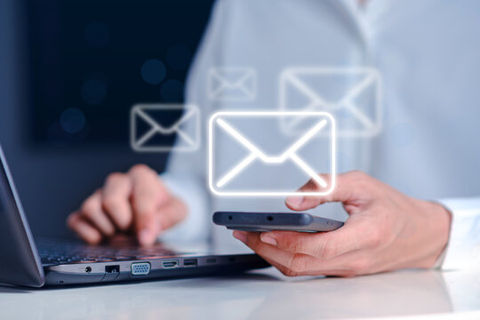 Person Checking Emails on Smartphone While Using Laptop at Desk - Powered by Adobe
