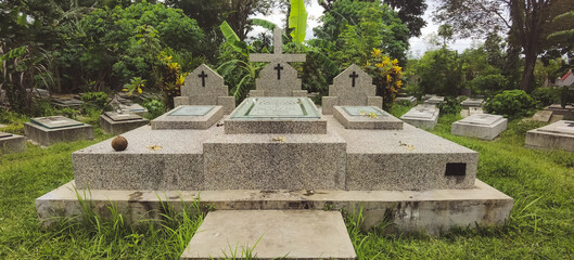 Tranquil cemetery view with stone monuments and lush greenery backdrop