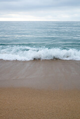 Waves crashing on the beach, cloudy spring day