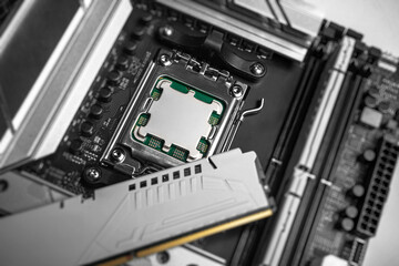 A computer processor is secured in its motherboard socket while a white RAM module is being positioned nearby during system assembly.