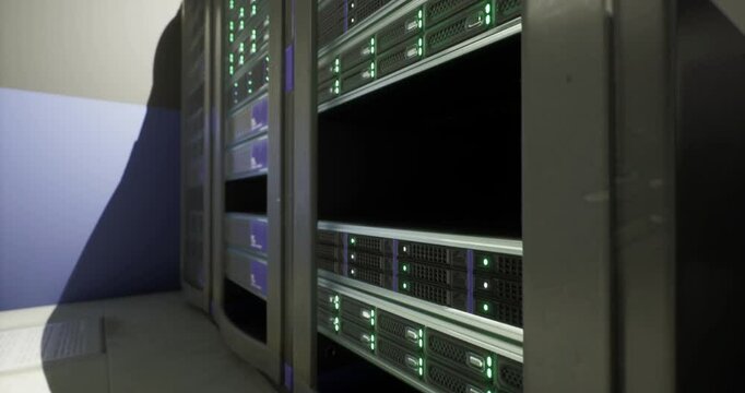 Rows of server racks in a data center are filled with glowing green lights, indicating active equipment. The setup suggests a high tech environment devoted to data processing.