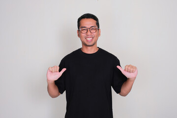 A man smiling proud while pointing at his plain black t'shirt that he wear