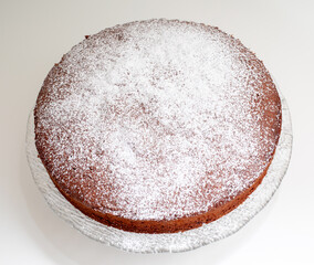 Delicious homemade caprese cake resting on a glass cake stand, sprinkled with powdered sugar