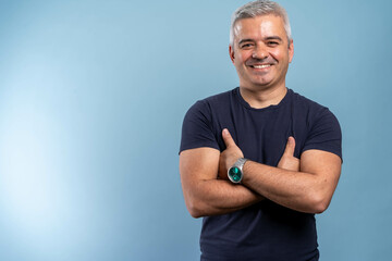 Caucasian handsome man isolated on blue background keeping the arms crossed in frontal position. Portrait of handsome smiling mature man with folded arms.
