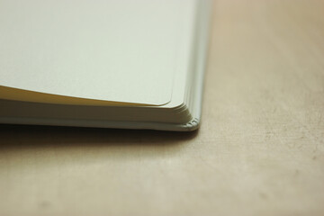 Fototapeta premium Macro view of blank book pages. Close up view of open white pages notebook. Round corners of the sketchbook. Old book on wooden background