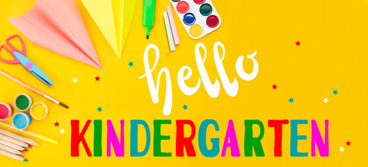 Hello kindergarten background. Top view flat lay concept. Childish lettering, colored paper, supplies, stationery for Pre-school, nursery school, kindergarten or preschool educational