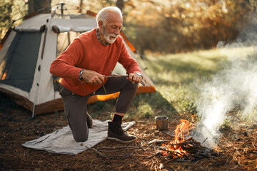 Elderly Man Enjoying Camping Adventure by Campfire in the Forest
