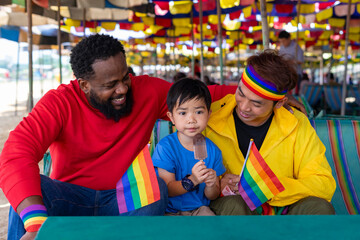 african and asian male gay couple sitting on beach chair are taking care boy kid son eating ice cream while travel on summer trip