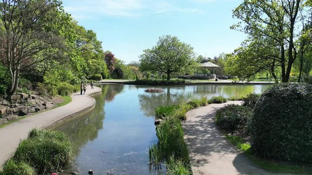 Greenhead Park Pond on a sunny Spring Day surrounded by trees in full bloom