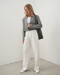 Stylish woman posing in a modern outfit with trousers and a blazer