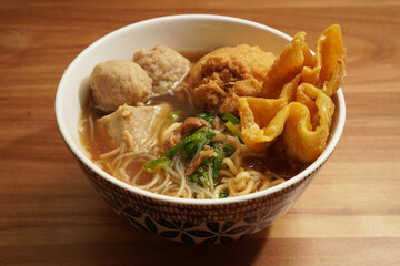 bakso, Indonesian meatballs served with noodles, tofu, and fried wontons (pangsit) on a wooden table