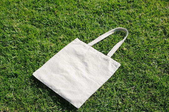 Canvas tote bag lying on green grass outdoor