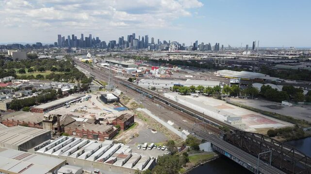 Aerial drone over industrial area, panning up to reveal Melbourne city skyline