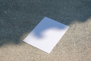 empty vertical paper poster mockup on concrete stone floor or pavement outdoors, shadow overlay
