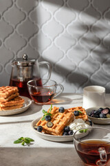 Waffles with fresh blueberries and cream in bright morning light. Healthy food, breakfast. Waffles with berries, text space.