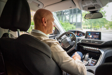 Close-up side view shot from inside a car of a mid aged man driving on road