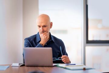 Mid aged businessman sitting at the office and having video call