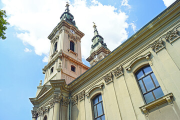 Fototapeta premium Photographed from the bottom up, the facade of a 19th-century temple with two bell towers and rich decoration in the Baroque and Classical styles. View of the main church in Pancevo, Vojvodina, Serbia
