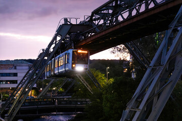 Eine Schwebebahn in der Abenddämmerung über dem Flussbett der Wupper in Elberfeld, Wuppertal, Deutschland