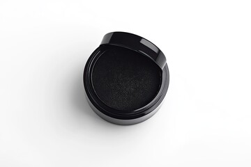 Black circular container with lid ajar, revealing dark powder inside