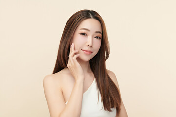 A beautiful young Asian woman with clean, fresh skin against a beige background. Skincare, facial treatment, cosmetology, beauty, and spa. An elegant portrait of an Asian woman.