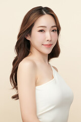 A beautiful young Asian woman with clean, fresh skin against a beige background. Skincare, facial treatment, cosmetology, beauty, and spa. An elegant portrait of an Asian woman.