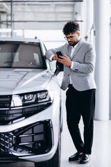 Business man choosing a car in car salon and talking on the phone
